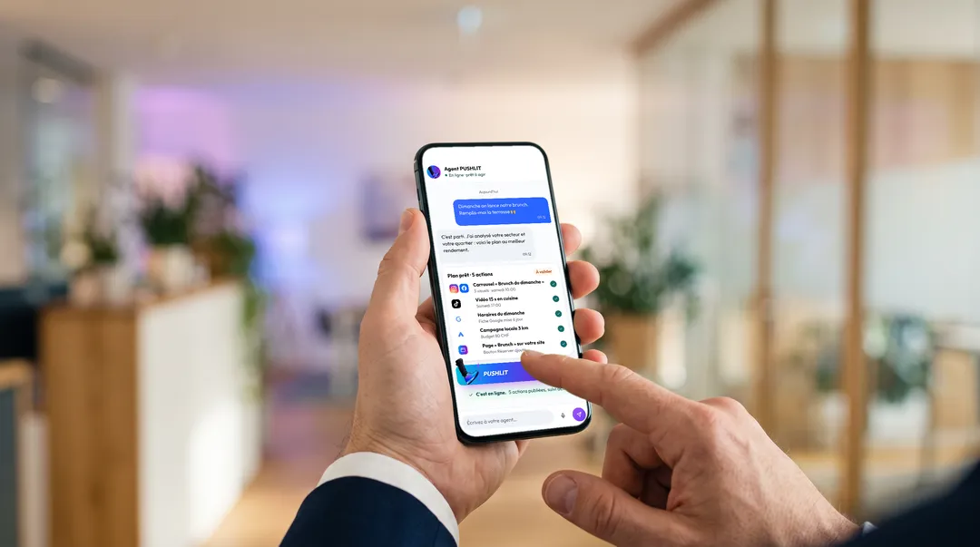 Ein Unternehmer hält sein Smartphone und tippt auf den PUSHLIT-Button, um den Plan des Agenten freizugeben