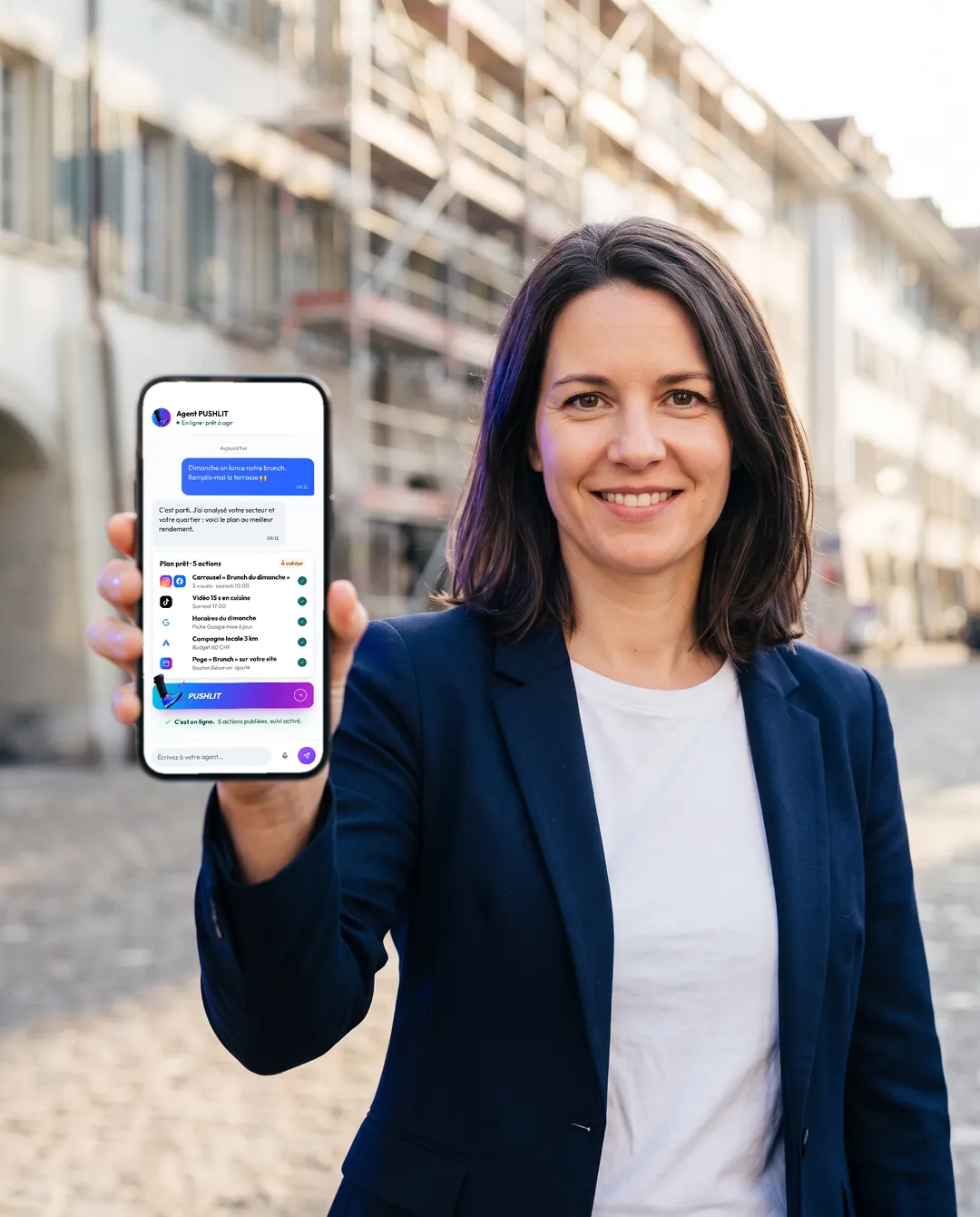 Entrepreneure dans la rue montrant le chat de l'agent PUSHLIT sur son téléphone